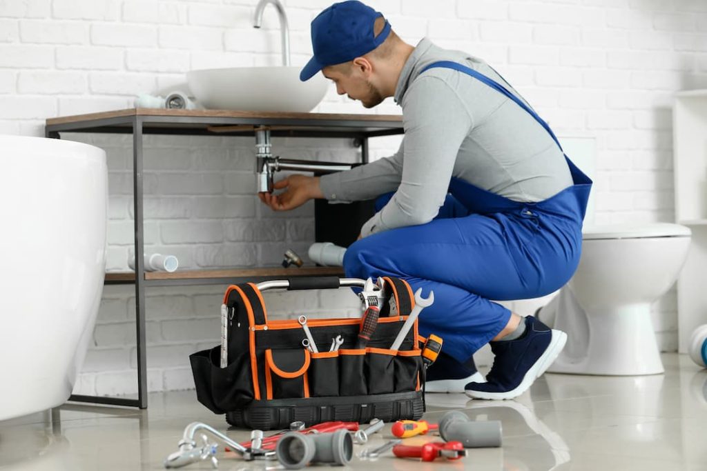 Plumbing inspecting pipes under sink